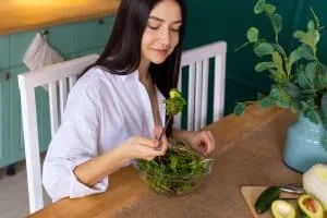 young-woman-eating-fresh-green-salad-at-the-kitche-2023-11-27-04-55-26-utc