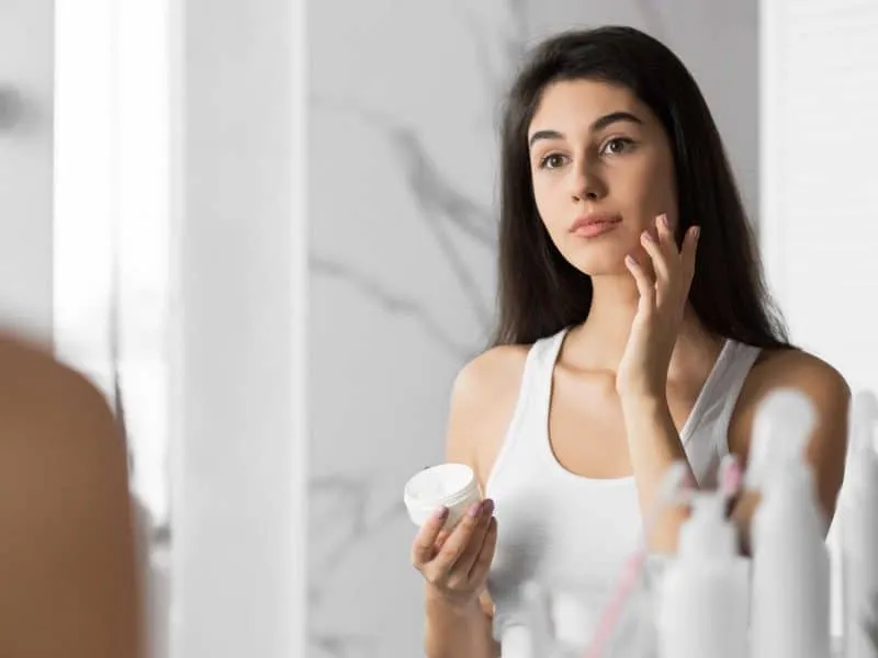 girl applying cream moisturizer on face