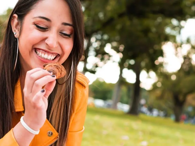 happy young woman sitting and eating on grass