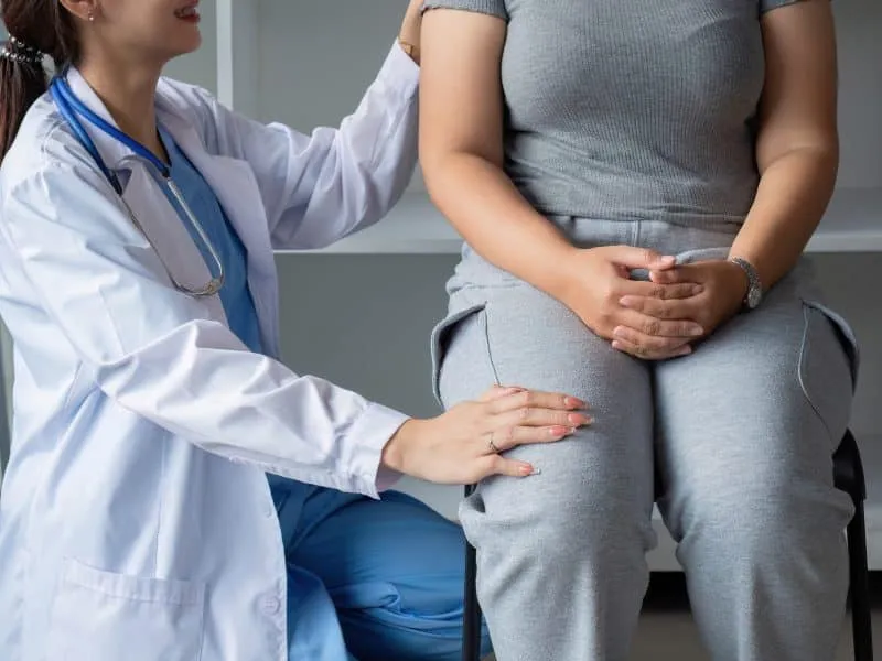 Female doctor and elderly female patient consulting about health problems in clinic.