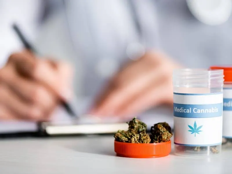 selective focus of dried weed and bottles with medical cannabis lettering near doctor writing