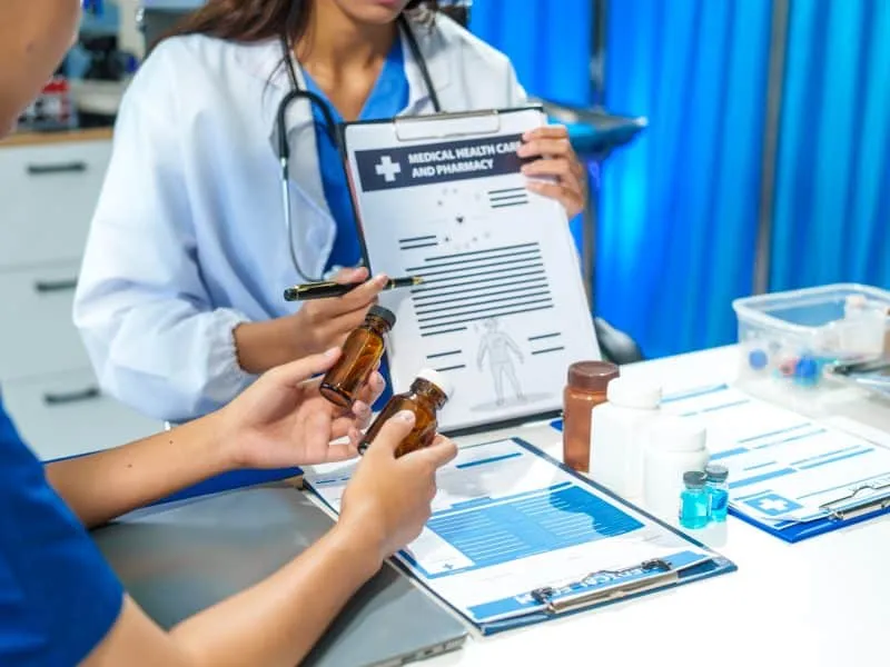 A close-up of two doctors discussing a bottle of medicine at a table in hospital.They collaborate