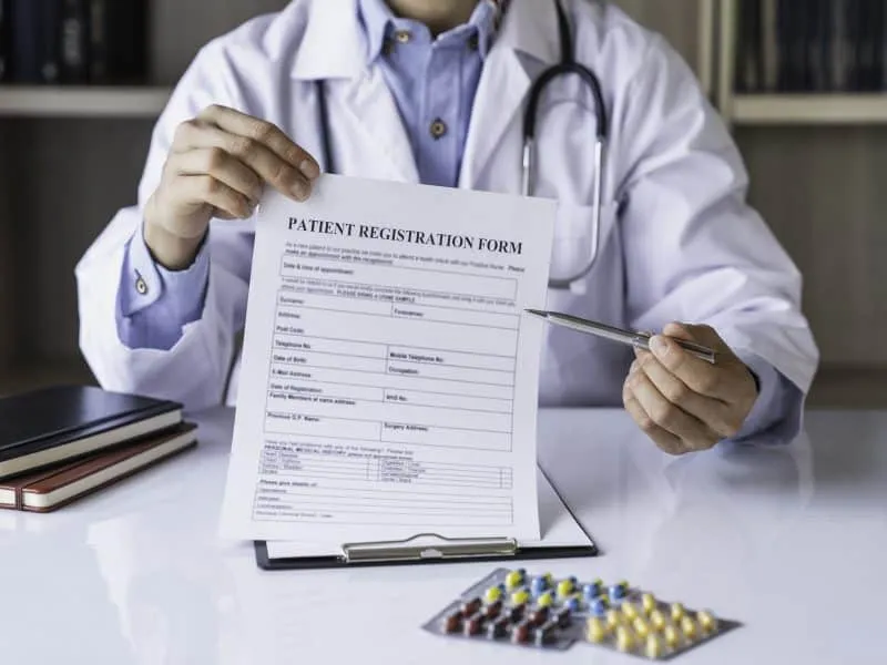 Close-up of the hand of a male doctor or pharmacist Holding the registration form and explaining it to the patient health and medical concepts