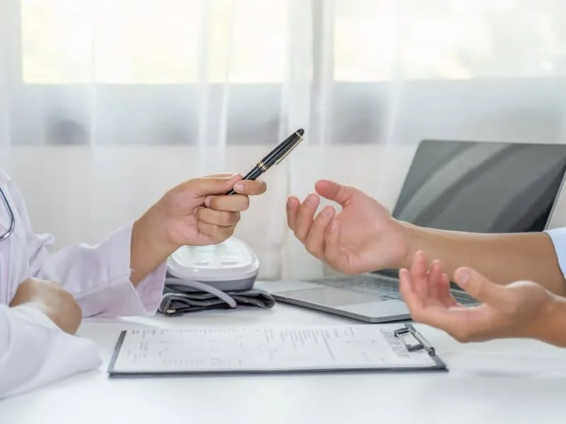 Doctor hand holding pen and explained examination results to the patient man, healthcare and medical checkup concept.