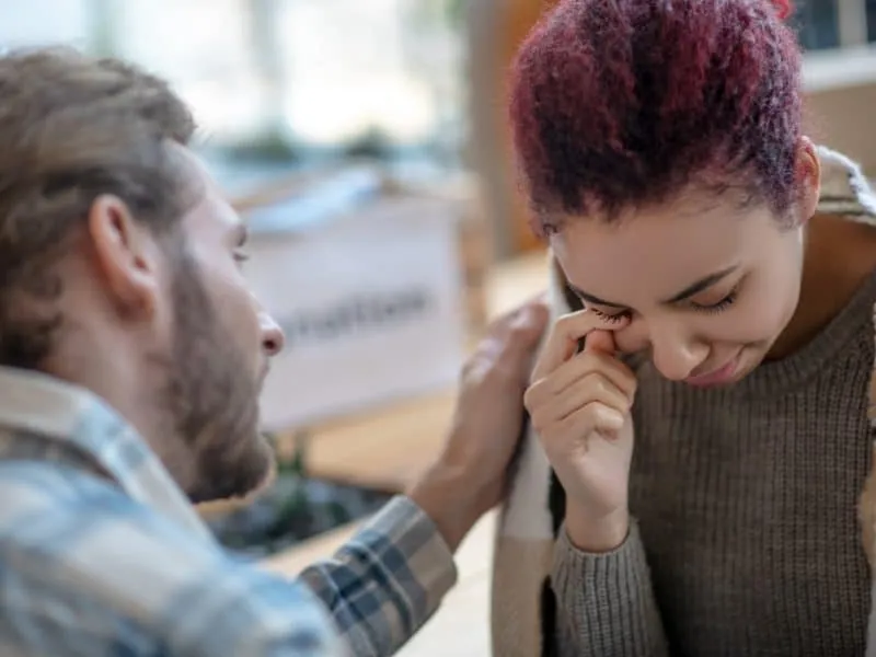 Tears. Crying young girl with colored hair, next to a man putting a hand on her shoulder soothing talking.
