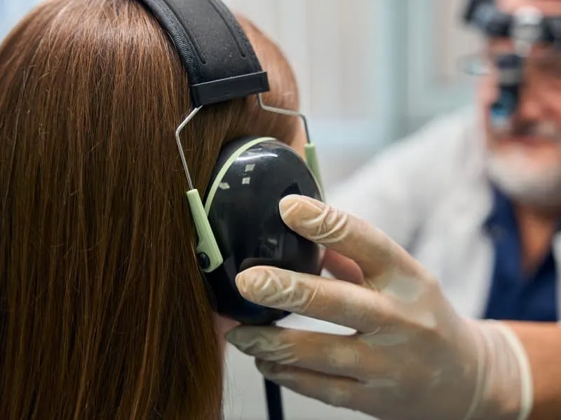 Elderly male caucasian doctor adjusting patient's headphones