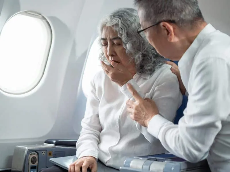 Mature with headache with nausea feeling sick while sitting in the airplane, Passengers near the window.