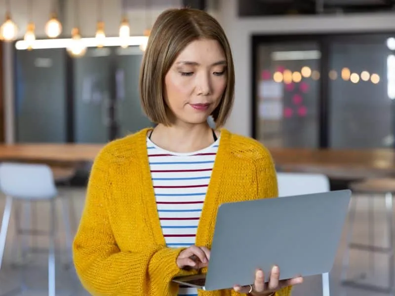 Portrait of asian businesswoman standing holding and using a laptop in office. independent creative design business.