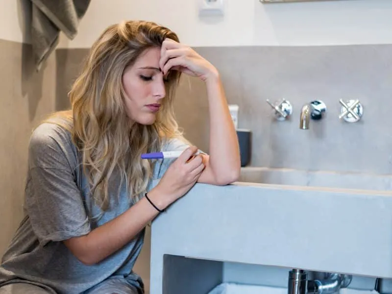 Worried sad woman Looking at a Pregnancy Test after results