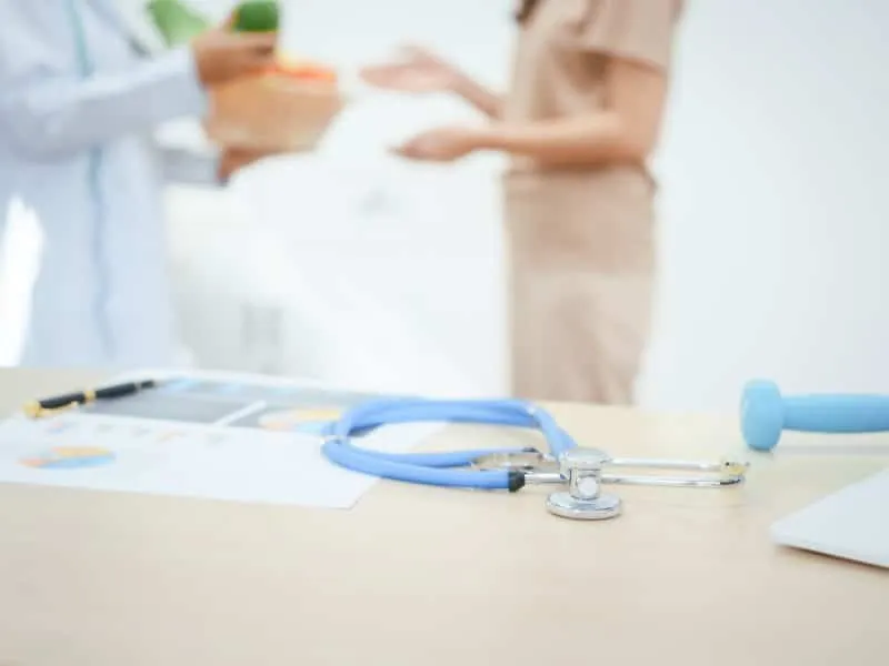 A young female nutritionist expert works at hospital desk,consulting female patients about eating