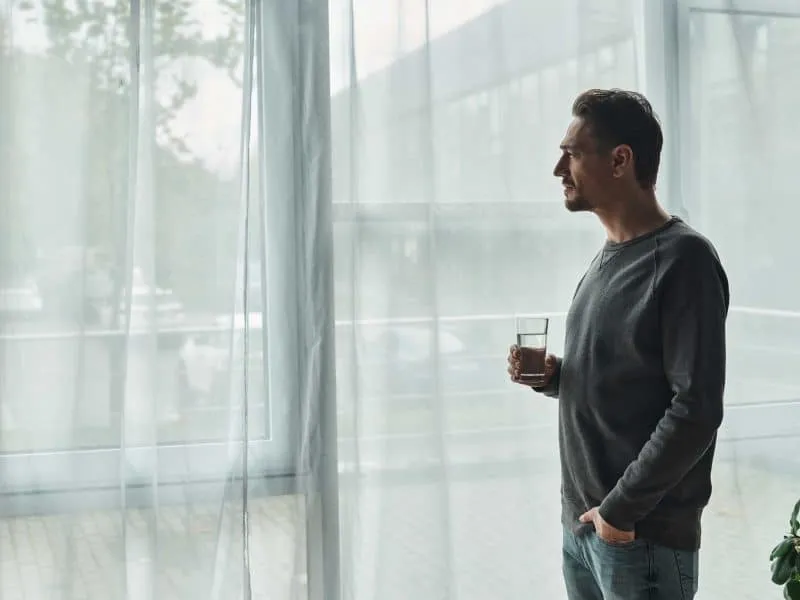 bearded man standing in front of windows