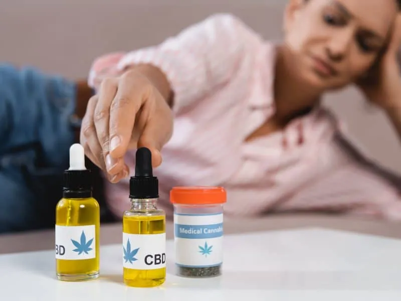 blurred african american woman reaching bottles with medical cannabis and cbd