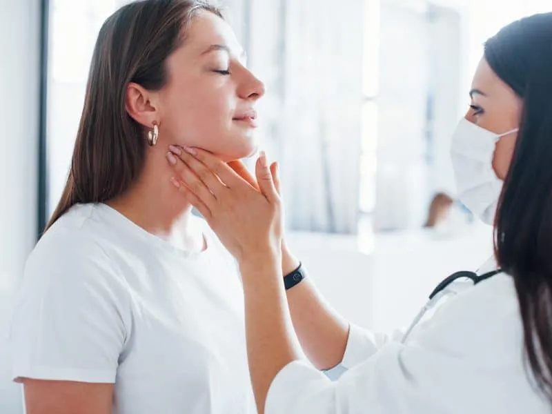 Checking lymph nodes and throat. Young woman have a visit with female doctor in modern clinic.
