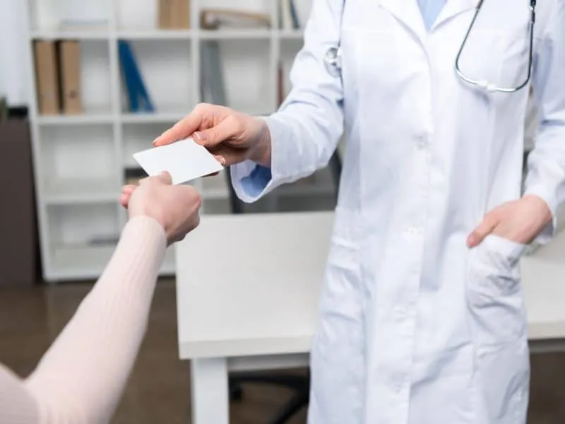 Cropped shot of doctor giving blank business card to patient
