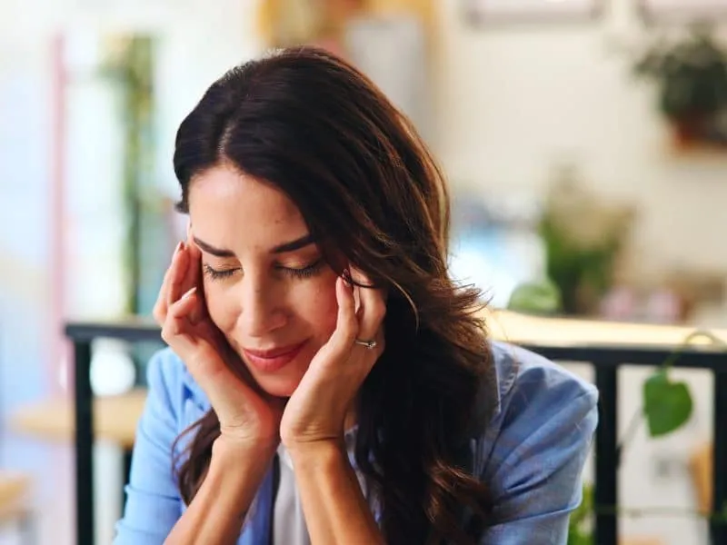 Pain, headache and woman in cafe with stress, sick or overwork with burnout for remote work. Migrai.