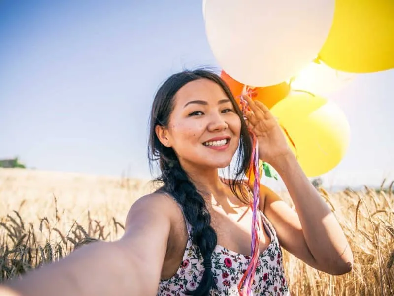woman with baloons taking selfie