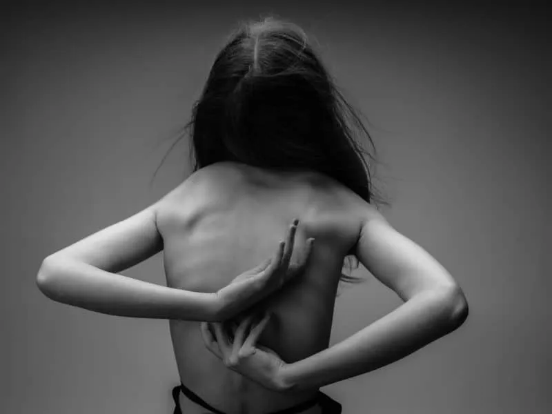woman with naked body standing with her back figure black and white background. High quality photo