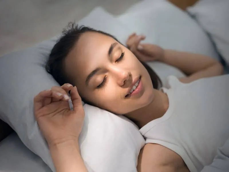 Young Woman Sleeping In Bed Comfortably And Blissfully With Sunbeam Dawn On Her Face