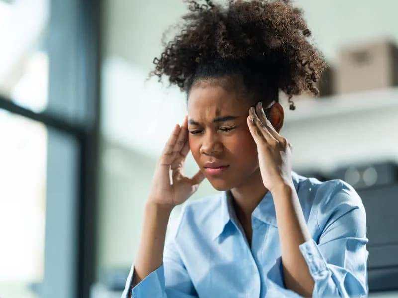A young African American woman with Afro brown hair in a modern office experiencing panic