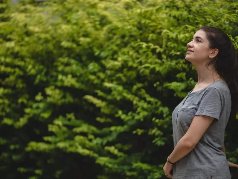 Carefree and young cheerful woman relaxing and enjoying while exercising on cycle outdoor in lane surrounded by greenery plants on a summer morning