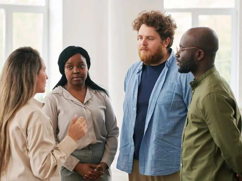 Group of young interracial people discussing their problems and giving advice to one another while attending course of psychological help