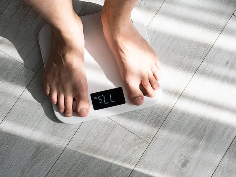 Boy legs stepping on floor scales at home. Weight control concept.