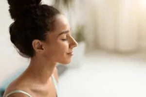 Mental Wellbeing. Closeup Shot Of Beautiful Calm Brunette Woman With Closed Eyes Standing Indoors, Portrait Of Peaceful Smiling Young Lady Meditating At Home, Enjoying Healthy Lifestyle, Copy Space