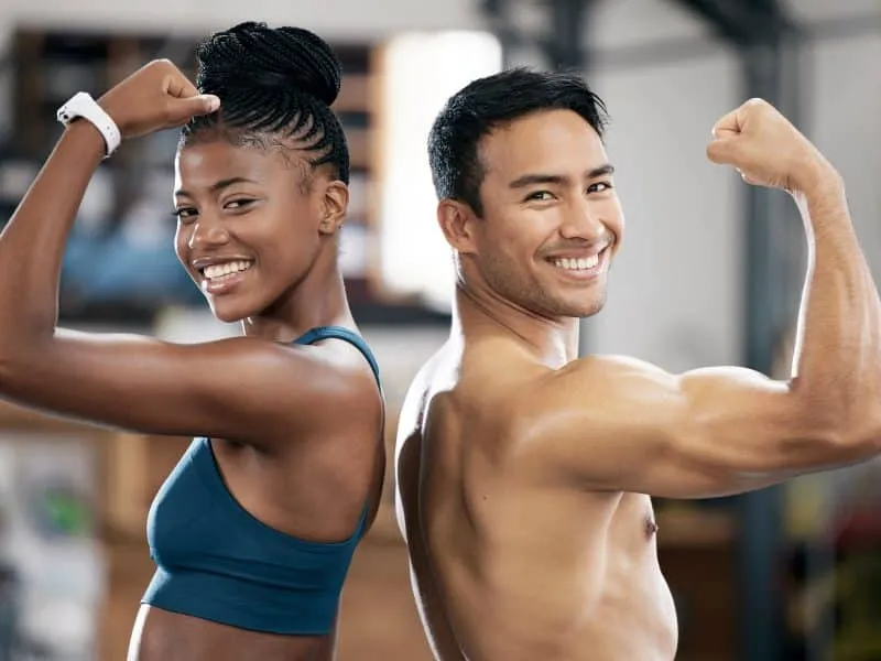 Portrait, black woman or coach flexing muscle or body goals in training or fitness exercise at gym