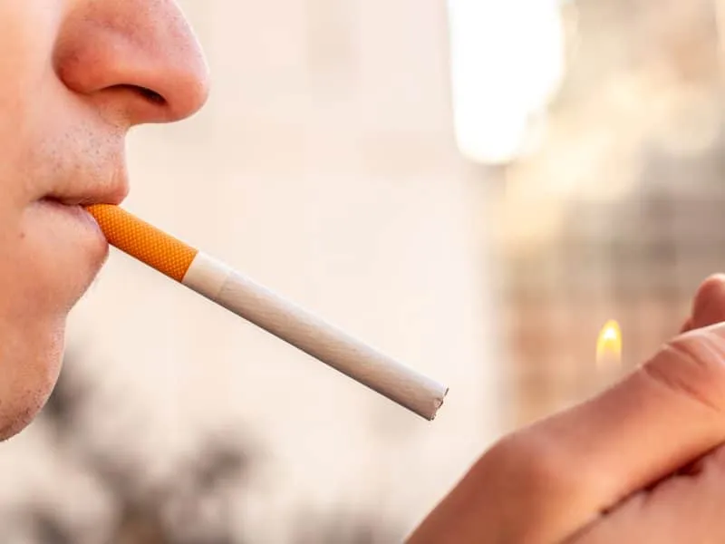 Smoking concept. Man lighting a cigarette with a lighter. High quality photo. Copy space. Smoking a cigarette close-up. Unhealthy lifestyle.