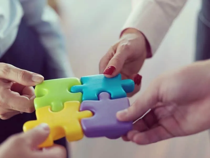 business people group assembling jigsaw puzzle and represent team support and help concept, top view at modern office interior