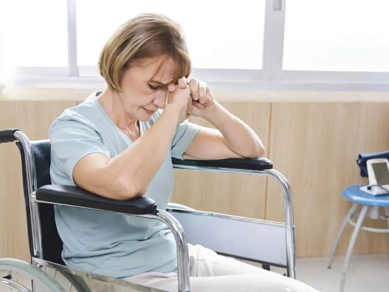 old woman patient in a wheelchair is discouraged and alone.