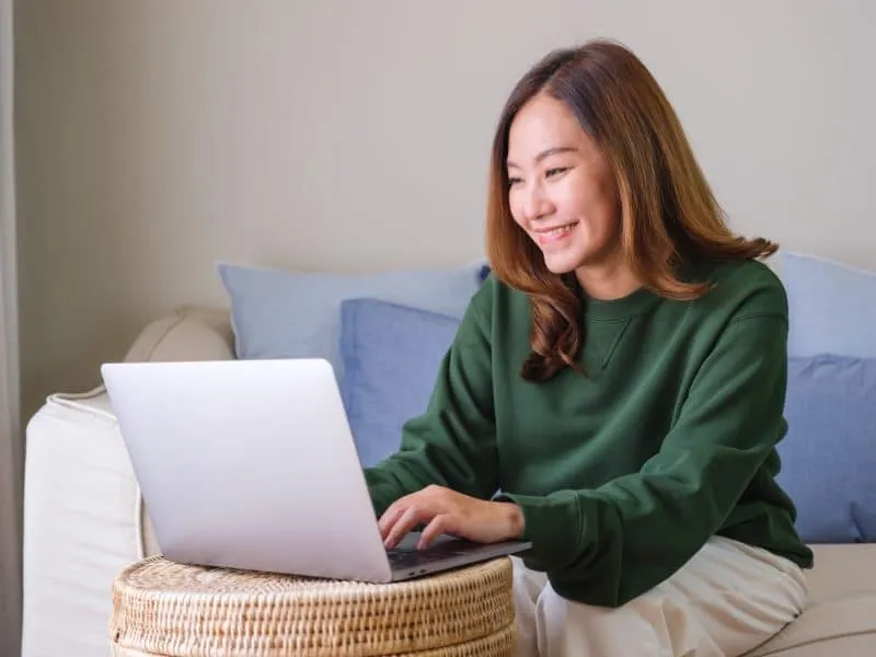 Portrait image of a young woman working on laptop computer at home