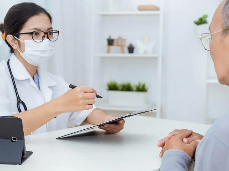 Portrait of asian woman doctor wear protection face mask showing a patient some information on digital tablet clip board, patient listen to specialist doctor in clinic office. Global alert, epidemic flu or Coronavirus. Medical staff preventive.