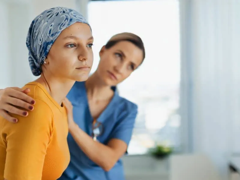 Teenage oncology patient talking with the doctor. Oncologist treating teen girl with cancer and provide emotional support, helping her with anxiety and depression.