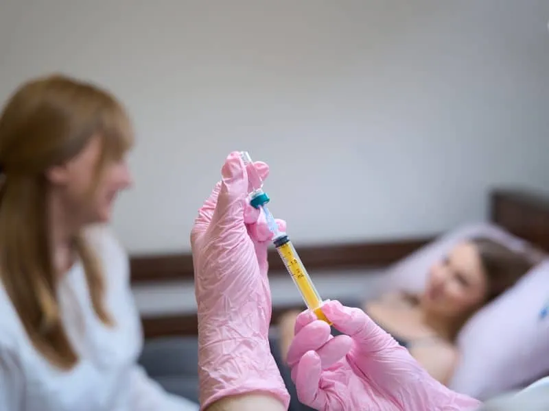 Doctor communicates with the patient in the hospital room, the nurse prepares the injection