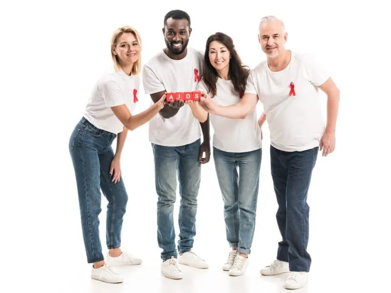 smiling multiethnic people in blank white t-shirts with aids awareness red ribbons holding blocks