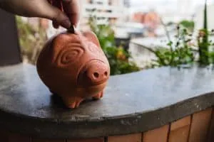 A closeup shot of a person putting a banknote into a piggy bank