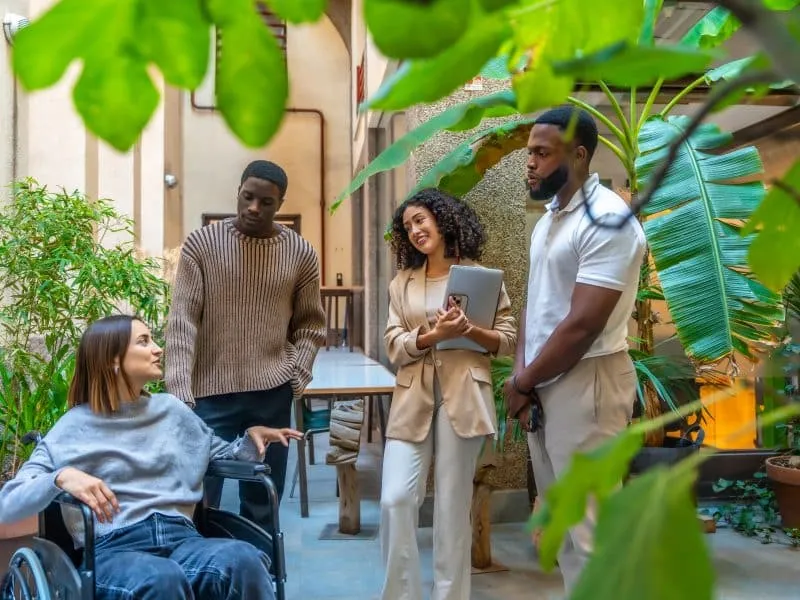 Full length photo of group of diverse colleagues talking in the patio of a modern coworking