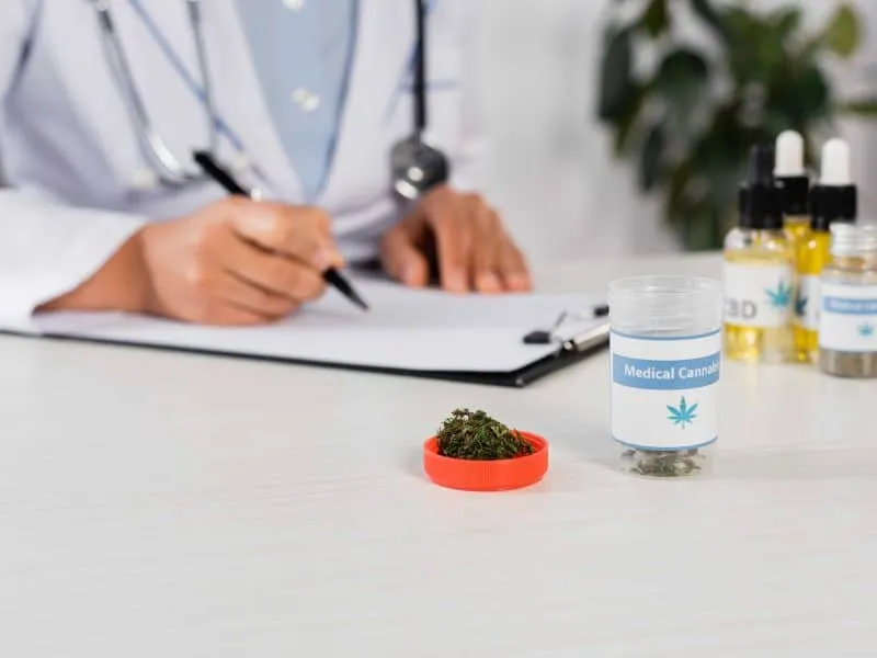 doctor writing on a paper and a medical cannabis and contaier on the table