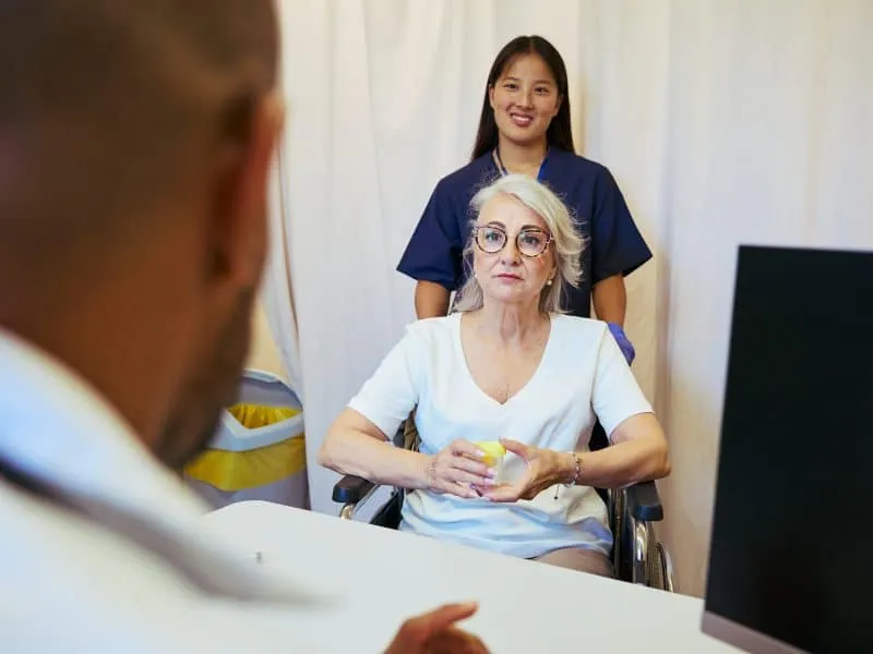 Medical professionals attending to an elderly patient in a wheelchair, emphasizing teamwork and healthcare in a hospital setting