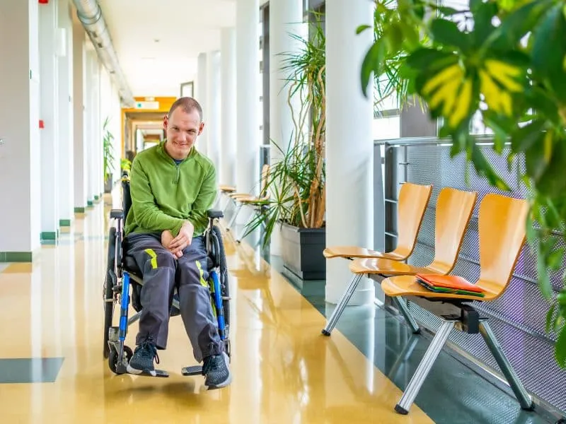 Full length portrait of a caucasian adult man with cerebral palsy sitting in an electrical wheelchair in the university
