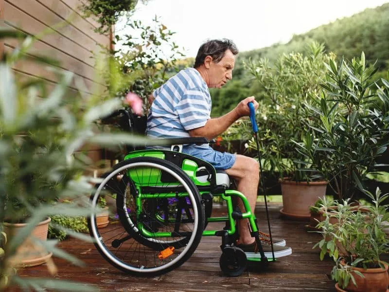 Side view of senior man in wheelchair doing exercise on terrace.