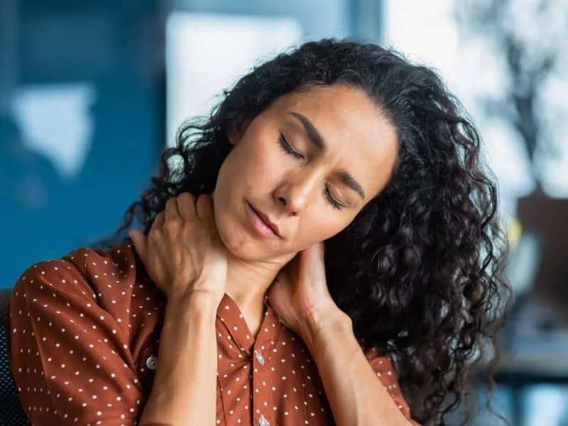 tired woman in the office holding her neck