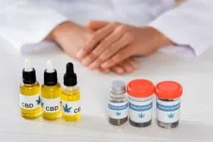 cropped view of doctor near bottles with legal cbd and medical cannabis