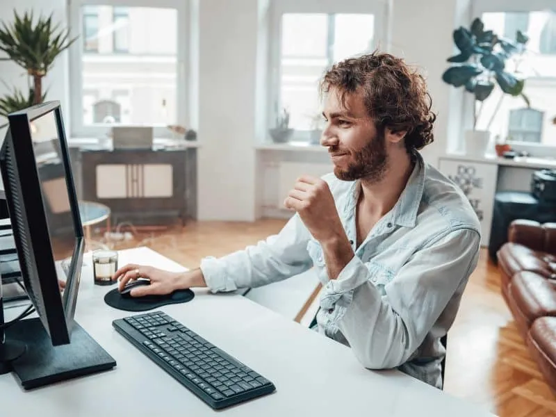 man sitting on his desk while using his computer