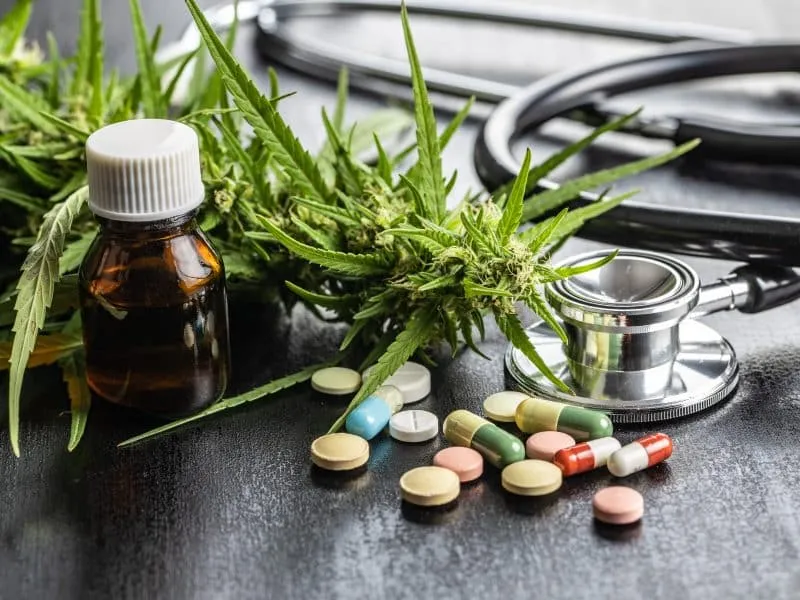Marijuana buds flowers of cannabis, stethoscope,pills and oil on black table.