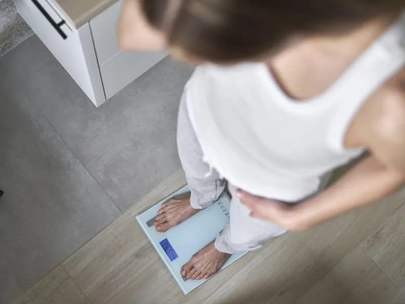 Top view of caucasian woman standing on bathroom scale