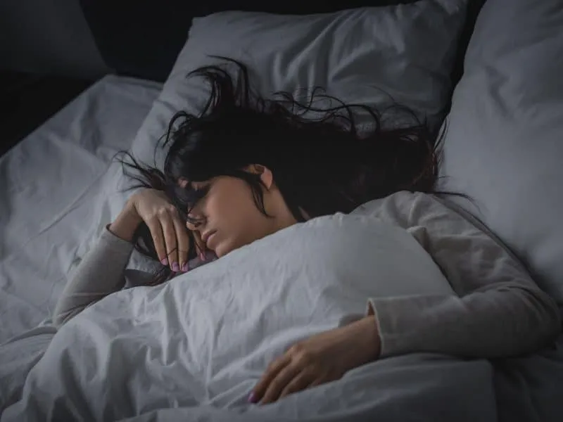 displeased woman having insomnia while lying on bed at night