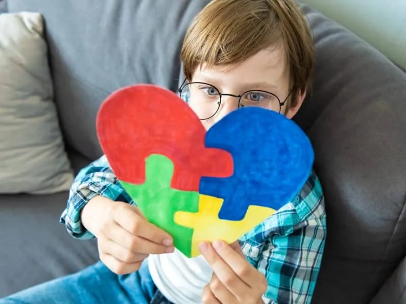 Preteen boy holding puzzle jigsaw heart shape, child mental health concept, world autism awareness day, teen autism spectrum disorder awareness concept