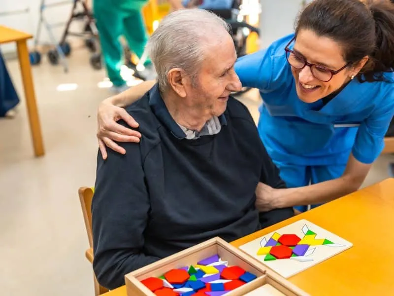 Senior man having fun with nurse playing board skill games in the geriatrics